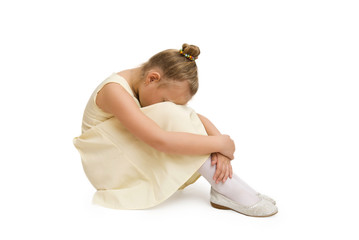 Portrait of unhappy little girl sitting on floor