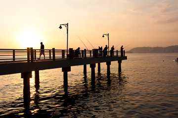 Fototapeta na wymiar Men fishing during the sunset in Santos, Brazil