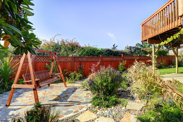 Fenced backyard with garden and hanging bench