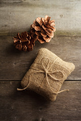 Still life of burlap wrapped present with pine cones