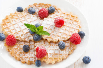 Belgian waffles with berries on white wooden table, close-up
