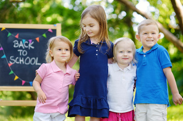 Four excited little kids by a chalkboard