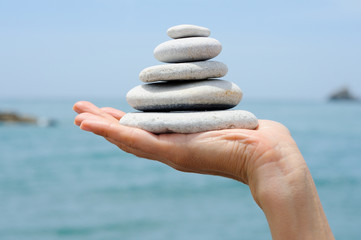 Gravel pile in woman's hands with sea background