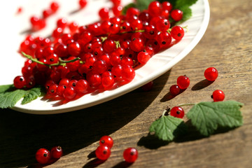 Fresh red currant in bowl on wooden background.