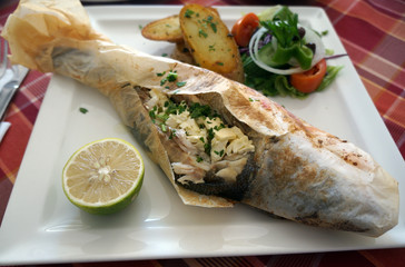 Sea bass baked in parchment on a white plate
