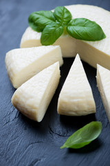 Sliced cheese and green basil leaves, close-up, vertical shot