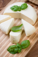 Close-up of sliced adygea cheese and green basil, vertical shot