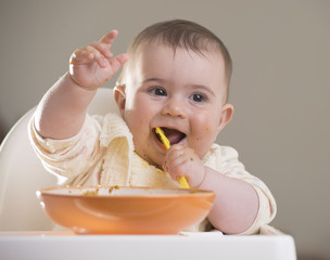 a cute baby girl laughing during meal time