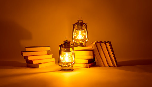 Burning kerosene lamps and books, concept magic of light