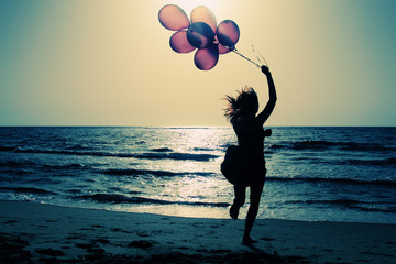 beautiful woman with colorful balloons on seaside