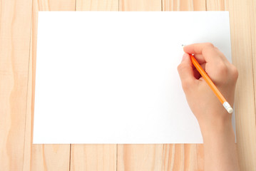 Woman hand with pencil and paper on wooden background .