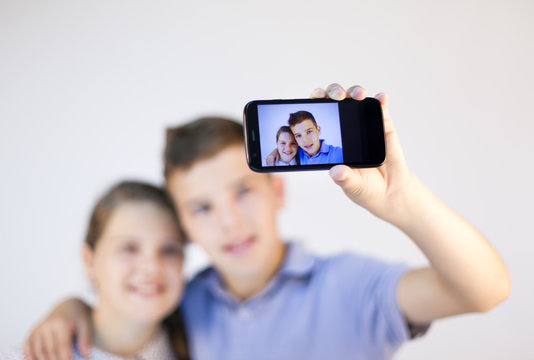 A boy and a girl taking a self portrait with smart phone against