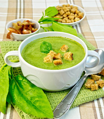 Soup puree with spinach and spoon on fabric