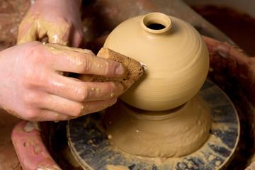 hands of a potter, creating an earthen jar