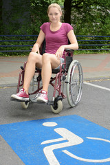 Frau im Rollstuhl auf Behinderten-Parkplatz