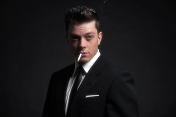 Retro fifties fashion man smoking a cigarette. Wearing black sui