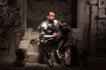 Medieval knight sitting on the steps of ancient temple