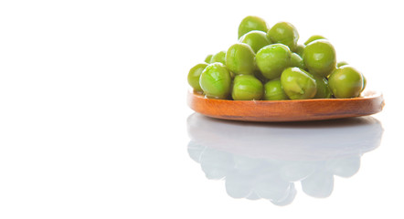 Green peas on wooden spoon over white background