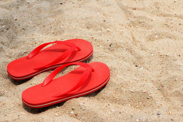 Fototapeta na wymiar red rubber flip-flops on the sand