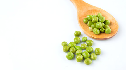 Green peas on wooden spoon over white background