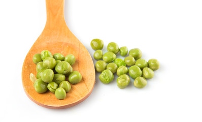 Female hand holding green peas on wooden spoon 