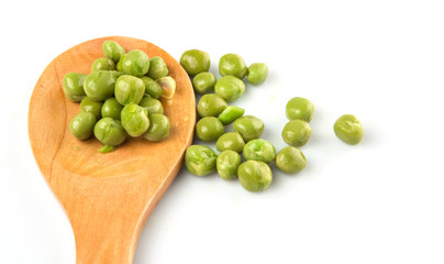 Green peas on wooden spoon over white background