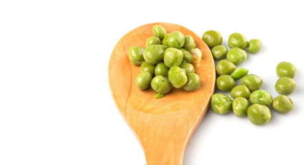 Green peas on wooden spoon over white background
