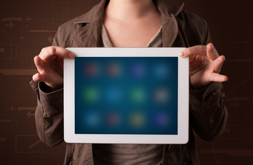 Woman holding a white tablet with blurry apps
