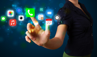 Young businesswoman pressing colorful mobile app icons with boke