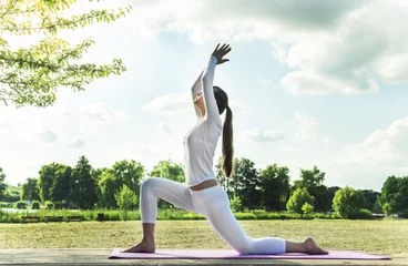 Muurstickers Mooie vrouw die yogaoefeningen in het park doet. © hammett79
