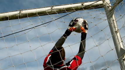 Goalkeeper in red saving a goal during a game