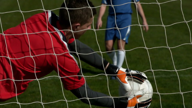 Goalkeeper in red saving a goal during a game