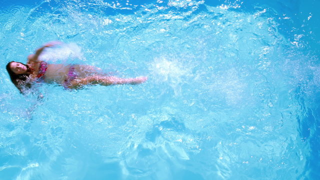 Overhead of brunette swimming in pool on sunny day