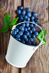 Blueberries from bucket on wooden background