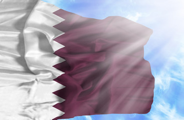 Qatar waving flag against blue sky with sunrays