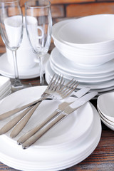 Set of white dishes on table on brick-wall background