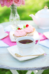 Coffee table with teacups and tasty cakes in garden