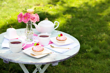Coffee table with teacups and tasty cakes in garden