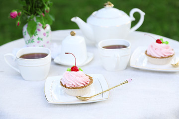 Coffee table with teacups and tasty cakes in garden