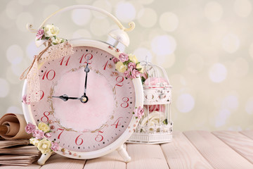 Beautiful vintage alarm clock with flowers on light background