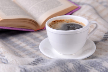 Cup of coffee on plaid with book
