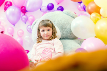 Fototapeta na wymiar Cute girl posing in playroom on balloons backdrop