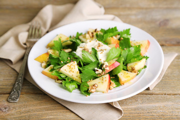 Green salad with apples, walnuts and cheese on wooden