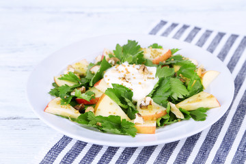 Green salad with apples, walnuts and cheese on wooden