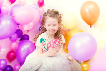 Obraz premium Adorable curly girl posing on balloons backdrop