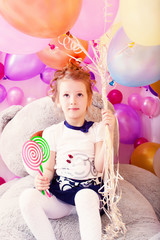 Funny girl holding lollipops and bunch of balloons