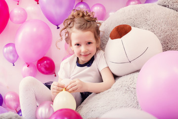 Smiling girl sits leaning on big teddy bear