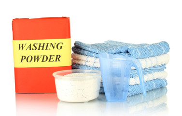 Box of washing powder with blue measuring cup and towels,