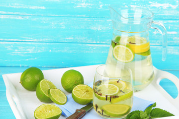 Fresh summer drink with lime and cloves in glass and jug,