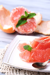 Ripe peeled grapefruits on plate, on color wooden background